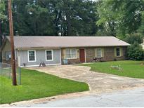 Charming single-story home featuring a metal roof, brick accents, and a spacious front yard with an extended driveway at 499 Oak Way, Lawrenceville, GA 30046