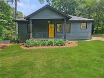 Charming exterior view of well-maintained home with inviting front yard and bright, welcoming, yellow front door at 1497 Elizabeth Ln, East Point, GA 30344