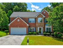 Beautiful two-story brick home with manicured lawn and attached two car garage, on a sunny day at 5025 Bishops Row Row, Austell, GA 30106