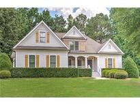 Charming two-story home with well-manicured lawn, beautiful shutters, and welcoming front porch at 4825 Whispering Pine Way, Cumming, GA 30028