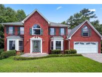 Charming two-story brick home featuring a well-maintained lawn, attached garage, and traditional architectural details at 1553 Smithson Ct, Lithonia, GA 30058