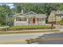 Charming bungalow with a red front door, lovely front porch, and freshly landscaped lawn at 1667 Sylvan Sw Rd, Atlanta, GA 30310