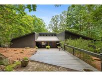 Charming home with a welcoming walkway, mature trees, and unique architectural details at 10775 Shallowford Rd, Roswell, GA 30075