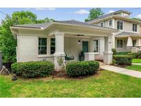 Charming bungalow featuring a covered front porch, swing, white brick, and manicured landscaping at 34 Montgomery Se St, Atlanta, GA 30317