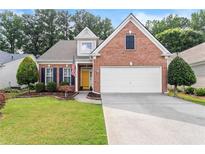 Charming brick home featuring a well-manicured lawn, attached two-car garage and inviting yellow front door at 3427 Hampreston Nw Way, Kennesaw, GA 30144