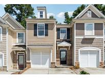 Charming townhome featuring a one car garage and neutral toned facade with black shutters and stone accents at 2130 Executive Dr, Duluth, GA 30096