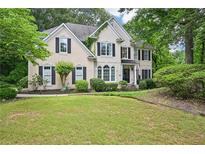 Charming two-story home featuring a manicured lawn and a traditional facade with black shutters and lush landscaping at 1285 Willow Park Way, Cumming, GA 30041