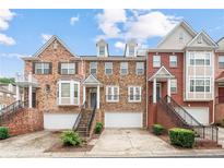 Charming townhomes featuring brick and stone exteriors, attached garages, and manicured landscaping at 10775 Brunson Dr, Johns Creek, GA 30097