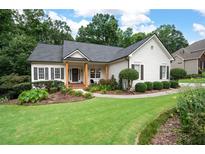 Charming one-story home featuring a lush lawn, manicured landscaping, and inviting front porch with wooden support columns at 6490 Ivey Hill Dr, Cumming, GA 30040