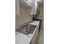Bright kitchen featuring a stainless steel sink, faucet, and countertop, complemented by white cabinetry at 6851 Roswell Rd # 15, Atlanta, GA 30328