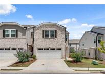 Charming two-story home with a two-car garage, brick facade, and landscaped front yard at 1542 Villageside Ct, Lawrenceville, GA 30043