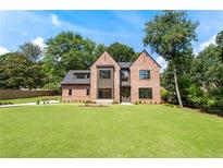 Stunning brick home showcasing modern design with large windows and a lush green lawn at 3711 Mountain Cove Rd, Snellville, GA 30039