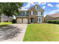Charming two-story home featuring a stone facade, two-car garage, manicured lawn, and classic curb appeal at 5420 Stevehaven Ln, Cumming, GA 30028