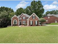 Charming brick home boasts a well-manicured lawn and mature trees, enhancing its curb appeal at 6630 Club Valley Ct, Suwanee, GA 30024
