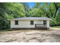 Charming single-story home with a wooden porch and simple landscaping surrounded by mature trees at 114 Howell Sw Dr, Atlanta, GA 30331