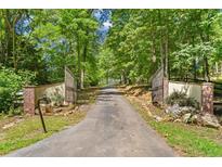 Gated driveway leads to the home, lined with mature trees and greenery at 639 Hall Station Rd, Kingston, GA 30145