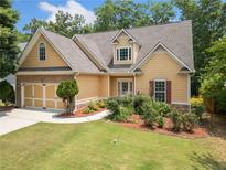 Inviting home with a well-manicured lawn, stone accents, and a two-car garage on a sunny day at 9996 Village South Dr, Douglasville, GA 30135