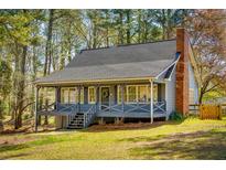 Charming blue home with a welcoming front porch and brick chimney, nestled among lush trees at 216 Hickory Way, Canton, GA 30115