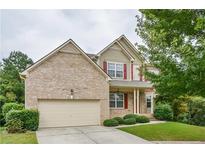 Charming two-story home featuring a brick facade, red shutters, a manicured lawn, and an attached two-car garage at 3439 Tupelo Trail, Auburn, GA 30011