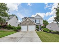 Charming two-story home with a stone accent facade, well-manicured lawn, and a two car garage at 142 Holly Mill Village Dr, Canton, GA 30114