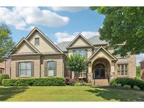 Inviting brick home featuring an arched entryway, manicured lawn, and lush landscaping in a desirable neighborhood at 2452 Stone Manor Ne Dr, Buford, GA 30519