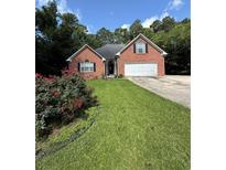 Charming single-story brick home featuring an attached two-car garage and a well-maintained lawn with lovely flower bushes at 709 Stonehenge Pl, Jonesboro, GA 30236