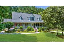 Charming brick home featuring a welcoming front porch, lush landscaping, and mature trees at 340 Helens Manor Dr, Lawrenceville, GA 30045