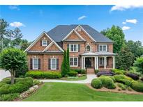Stately brick home featuring manicured landscaping, a covered porch, and a classic architectural design at 7025 Windsor Hill Psge, Suwanee, GA 30024