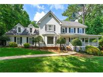 Beautiful two-story home with a covered front porch, mature trees, and manicured landscaping at 440 Junction Trak, Roswell, GA 30075