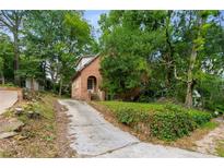 Charming brick home with arched entryway and mature trees lining the driveway at 1200 Mansfield Ne Ave, Atlanta, GA 30307