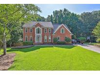 Charming brick two-story home featuring a well-manicured lawn and mature trees at 1875 Edgemont Ct, Cumming, GA 30041