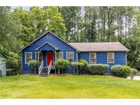 Charming blue home with a red front door and a lush green lawn and mature shade trees at 178 Castleair Ne Dr, Kennesaw, GA 30144
