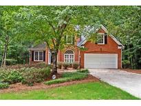 Charming brick home featuring a two-car garage and well-maintained landscaping, surrounded by lush trees at 1765 Redbud Way, Cumming, GA 30041
