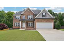 Charming two-story brick home featuring a well-manicured lawn, attached two car garage and inviting front entrance at 2359 Saint Kennedy Ln, Buford, GA 30518