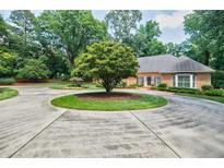 Stately brick home with circular driveway and mature landscaping, perfect for curb appeal at 3030 Spalding Dr, Sandy Springs, GA 30350
