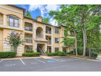Exterior of a tan condo with a parking lot, trees, and multiple levels of balconies at 3777 Peachtree Ne Rd # 438, Brookhaven, GA 30319