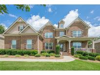 Charming brick home featuring manicured lawn, lush shrubs and a welcoming front porch at 5515 Cheatam Ave, Cumming, GA 30040