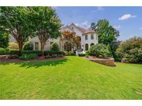 Beautiful front yard featuring lush green grass, trees, and well-maintained landscaping at 4115 Falls Ridge Dr, Johns Creek, GA 30022