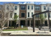 A modern three-story townhouse with white and brown accents, set against a backdrop of lush greenery at 358 Olmstead Way # 25, Alpharetta, GA 30022