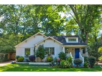 Charming home with white brick, blue door, lush lawn and mature trees at 135 Martha Ne Ave, Atlanta, GA 30317