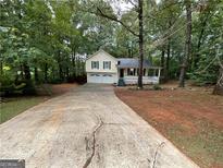 Charming yellow two-story home with a two-car garage and inviting front porch surrounded by lush trees at 48 Glenhaven Ct, Douglasville, GA 30134