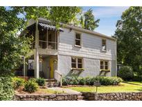 Charming home with a welcoming yellow front door, a screened porch, and a beautifully landscaped yard at 3158 Granby Ave, Scottdale, GA 30079