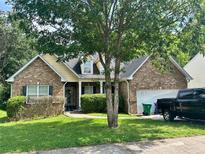 Charming brick home featuring a well-manicured lawn, mature trees, and an attached two-car garage at 6941 Roane Ct, Lithonia, GA 30038