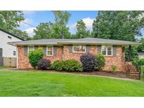Charming brick home features a well-manicured lawn and lush landscaping, enhancing curb appeal at 1315 Merry Ne Ln, Atlanta, GA 30329