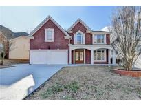 Charming two-story brick home featuring a two-car garage and a beautifully landscaped front yard at 1417 Wind Chime Ct, Lawrenceville, GA 30045