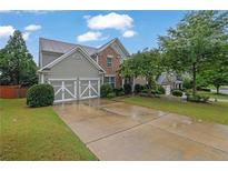 Charming two-story home featuring a brick facade, well-manicured lawn, and a two-car garage at 202 Roseman Way, Woodstock, GA 30188