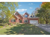 Charming brick home featuring a well-manicured lawn, mature trees, and a two-car garage at 2335 Corbett Ct, Powder Springs, GA 30127