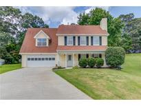 Charming two-story home with attached garage, manicured lawn, and traditional design elements at 932 Sugar Meadow Ln, Sugar Hill, GA 30518