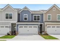 Charming townhome with a two-car garage, colorful siding, and a well-maintained front lawn at 1181 Chastain Dr, Sugar Hill, GA 30518