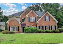 Charming brick two-story home with manicured lawn, lush greenery, and dark shutters at 1868 Birch Briar Bnd, Lawrenceville, GA 30043